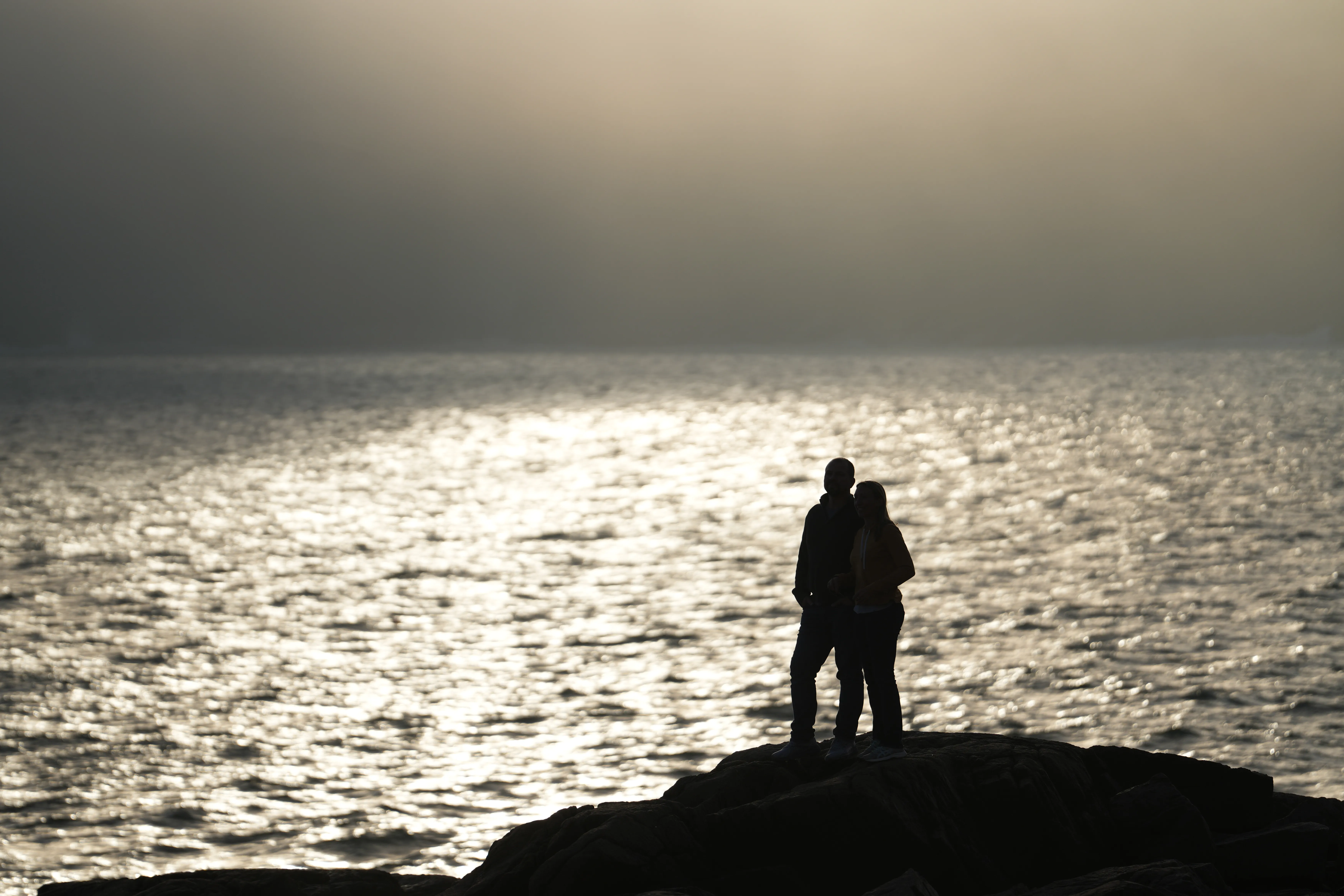 A couple silhouetted against shimmering water at golden hour